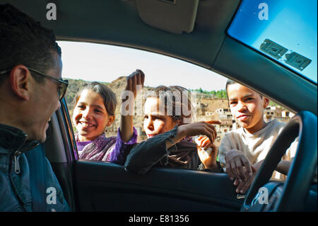 Horizontal portrait of an attractive Moroccan man giving out sweets and money to children in the High Atlas Mountains in Morocco Stock Photo