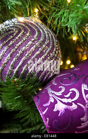 Vertical close up of brightly coloured ornamental Christmas decorations on the real pine tree. Stock Photo