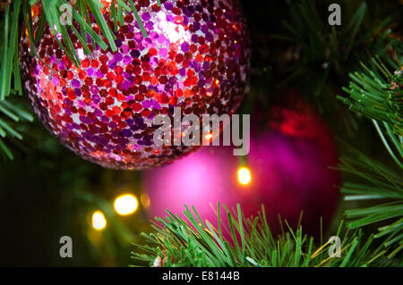 Horizontal close up of brightly coloured ornamental Christmas decorations on the real pine tree. Stock Photo