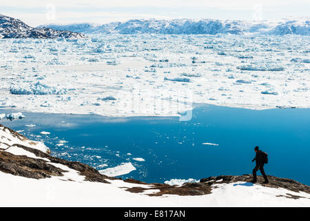 Hiker treks along the coast by snowy waters Stock Photo