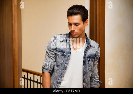 Attractive young man indoors, leaning against door jamb Stock Photo