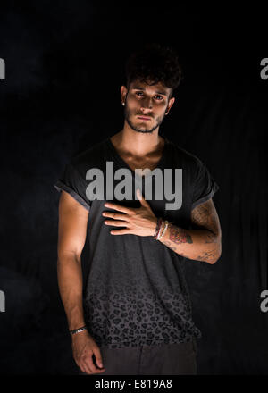 Portrait of handsome young man in dark t-shirt on black background. Dramatic lighting Stock Photo