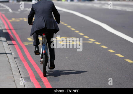 A man in a suit riding over Waterloo Bridge, in a bus lane, in London Stock Photo