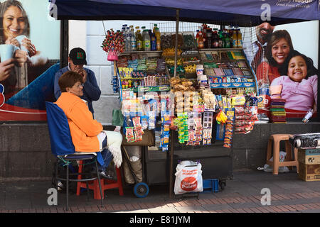 Woman sitting at small snack and drink cart on Chile street in the city center in Quito, Ecuador Stock Photo