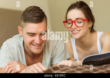 Cute couple reading newspaper in bed Stock Photo