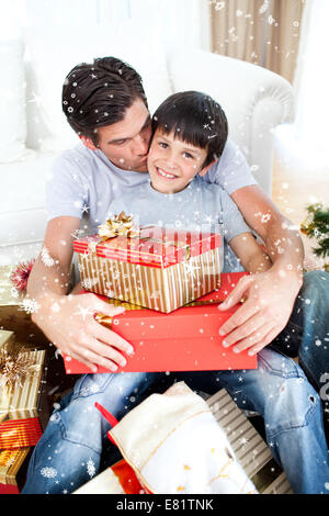 Composite image of father kissing his son after giving him a christmas gift Stock Photo