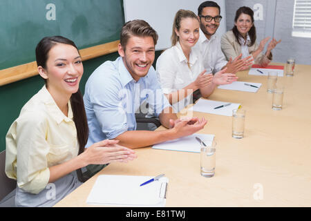 Business team sitting in a row clapping at camera Stock Photo