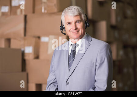 Businessman using headset in warehouse Stock Photo