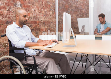 Focused businessman in wheelchair working at his desk Stock Photo