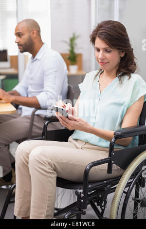 Businesswoman in wheelchair texting on phone Stock Photo