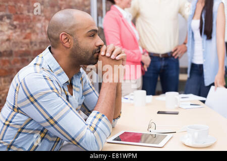 Focused man sitting at desk using his tablet Stock Photo