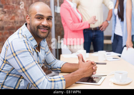 Smiling man sitting at desk using his tablet Stock Photo