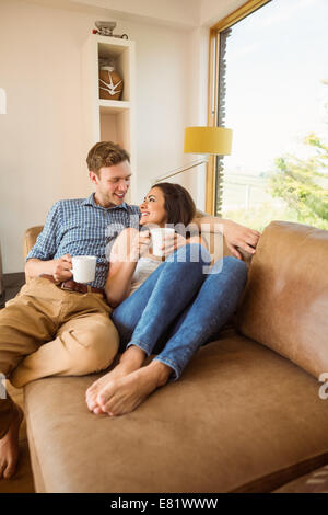 Couple Relaxing On Sofa With Hot Drink In New Home Stock Photo - Alamy