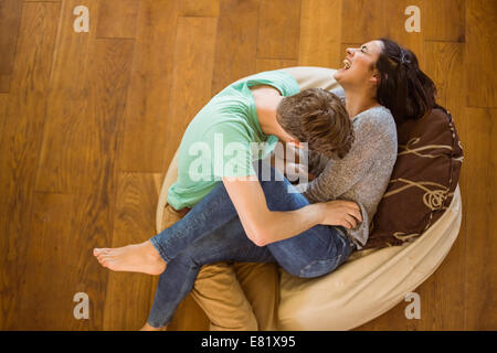 Cute couple laughing together on beanbag Stock Photo