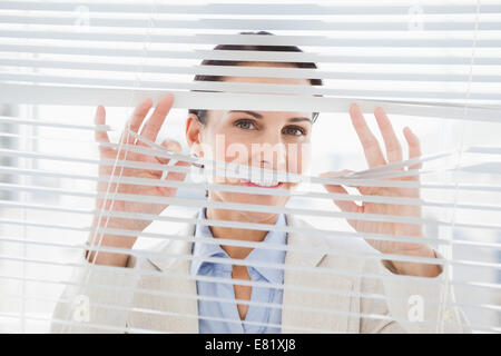 Woman glancing through some blinds Stock Photo