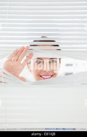Woman looking out through blinds Stock Photo
