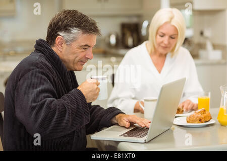 Mature couple having breakfast together man using laptop Stock Photo