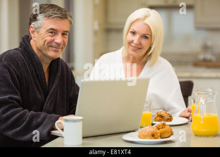 Mature couple having breakfast together man using laptop Stock Photo
