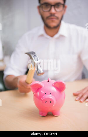 Man breaking piggy bank with hammer Stock Photo