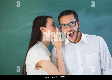 Casual woman whispering secret into friends ear Stock Photo