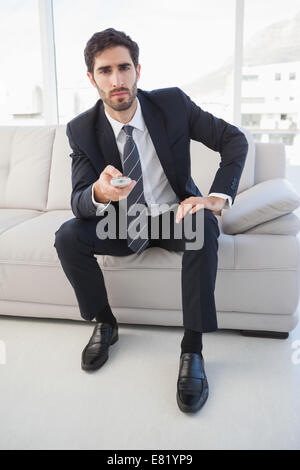 Businessman holding a tv remote Stock Photo