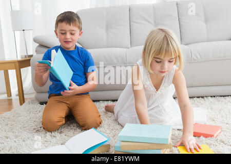 Siblings sitting on the floor reading storybook Stock Photo