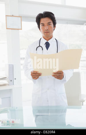 Serious looking doctor with medical files Stock Photo