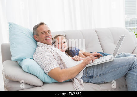 Father with daughter relaxing on the couch using laptop Stock Photo