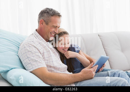 Father with daughter relaxing on the couch using laptop Stock Photo