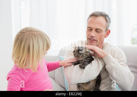 Happy daughter and father sitting with pet kitten together Stock Photo