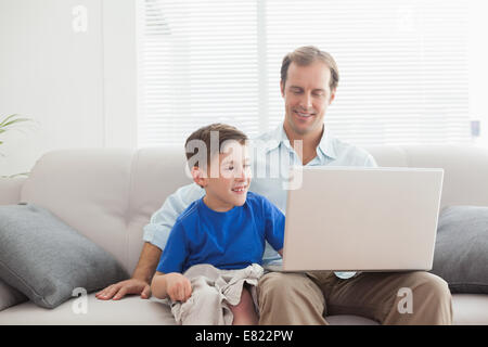 Father and son using laptop on the couch Stock Photo