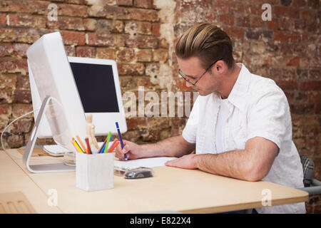 Handsome happy man using computer taking notes Stock Photo