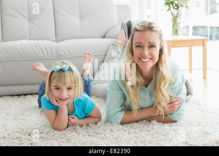 Smiling daughter and mother laying on the floor Stock Photo