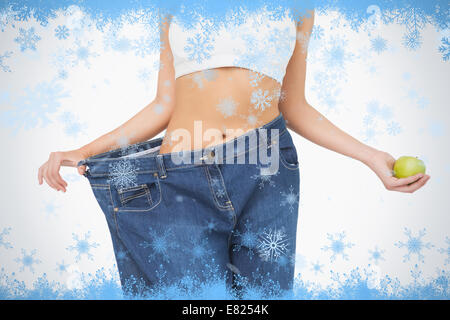 Mid section of slim woman wearing too big jeans holding an apple Stock Photo