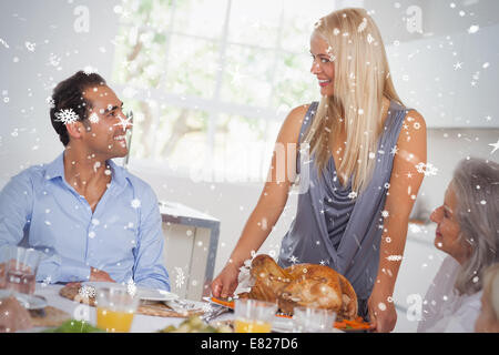 Composite image of happy wife bringing turkey to the table Stock Photo