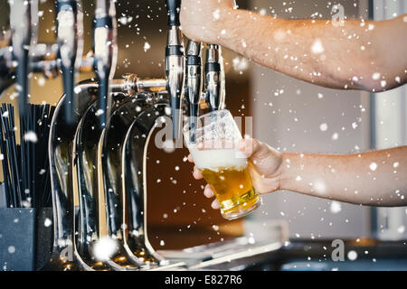 Composite image of barmans arms pulling a pint of beer Stock Photo