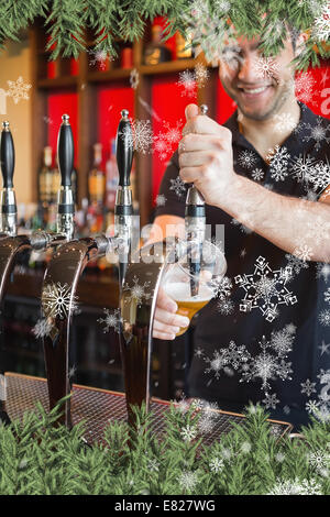 Composite image of handsome barkeeper pulling a pint of beer Stock Photo
