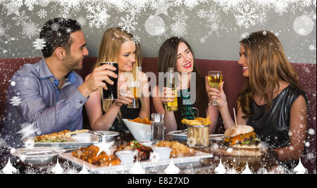 Composite image of happy friends sitting together having dinner Stock Photo