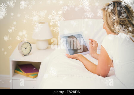 Thoughtful woman using a tablet pc lying on her bed Stock Photo
