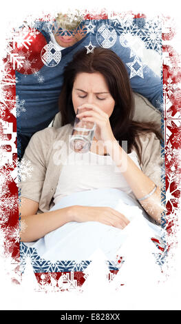 Composite image of sick woman drinking water lying on the sofa Stock Photo