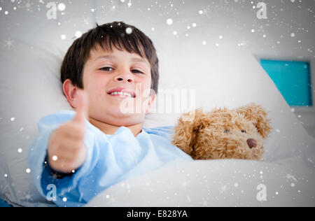 Composite image of little boy hugging a teddy bear lying in a hospital bed Stock Photo