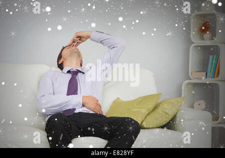 Tired businessman sitting on sofa in living room Stock Photo