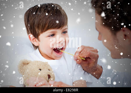 Composite image of positive doctor taking little boys temperature Stock Photo