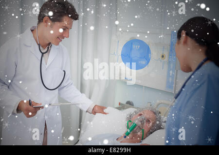 Doctor and nurse checking patient lying under digital screen showing ecg data Stock Photo