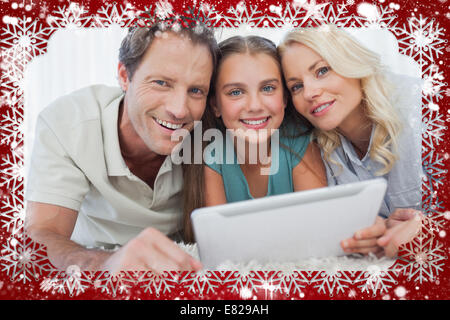 Composite image of portrait of a girl and her parents using a tablet Stock Photo