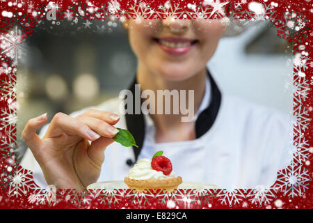 Smiling head chef putting mint leaf on little cake on plate Stock Photo