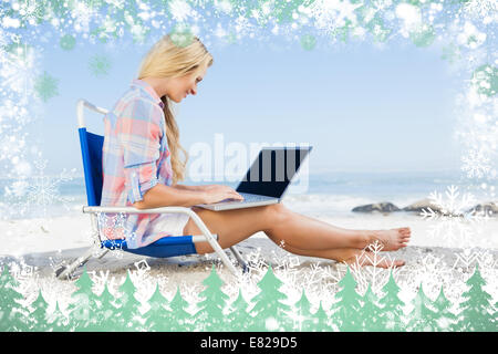 Woman sitting on beach using her laptop Stock Photo