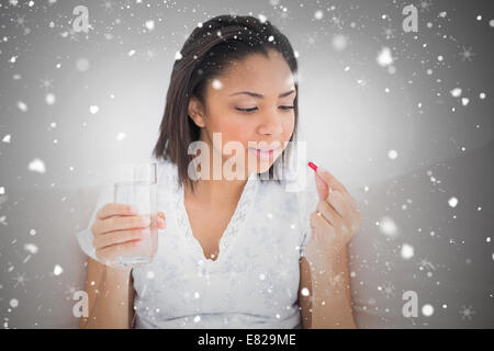 Unsmiling young dark haired model taking medication Stock Photo