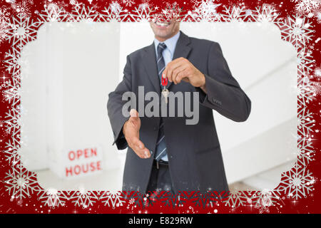 Businessman offering a handshake while holding up keys Stock Photo