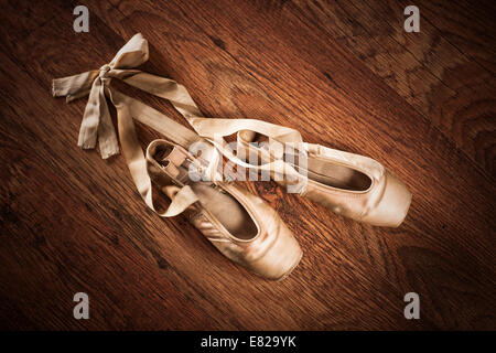 Pair of worn out ballet shoes on a wooden floor Stock Photo